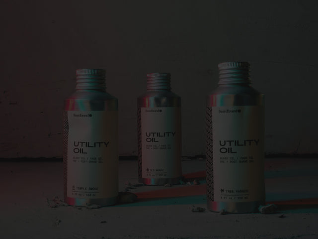 3 bottles of Utility Oil showing off their dents on a concrete background with red and blue lighting.